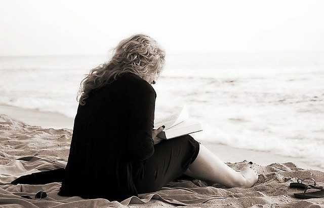mulher-lendo-livro-sentada-na-areia-da-praia-em-preto-e-branco